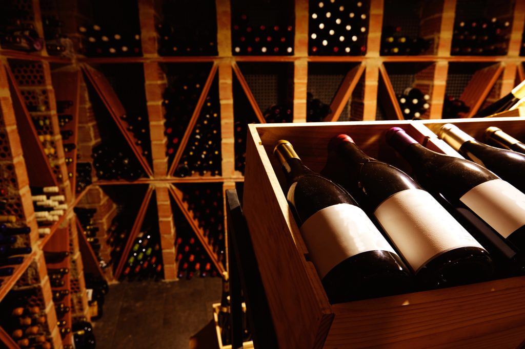 Dark and stylish wine cellar in background with closeup of bottles in foreground