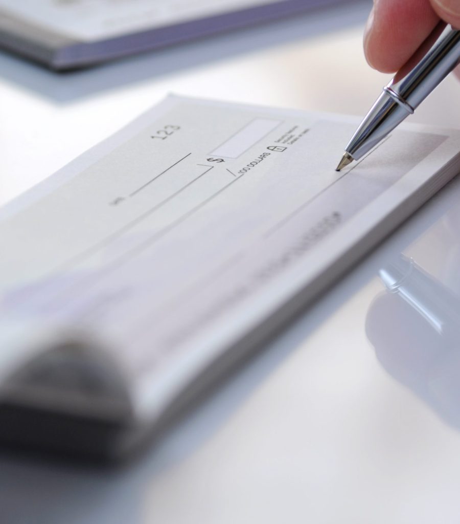 Close-up businessman hand hold pen fill a banque cheque document Prepare writing a check in office