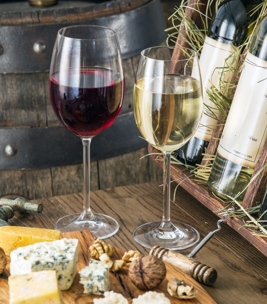 two glasses of wine with soft cheese laid out and an open display box of wine bottles in the background